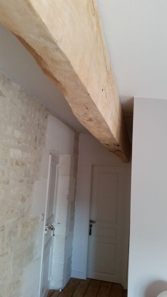 poutre au plafond et pierres au mur dans la maison